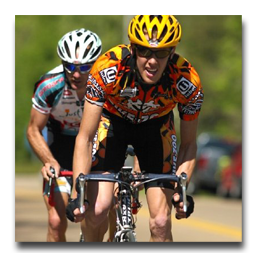 A man wearing a yellow helmet is riding a bike