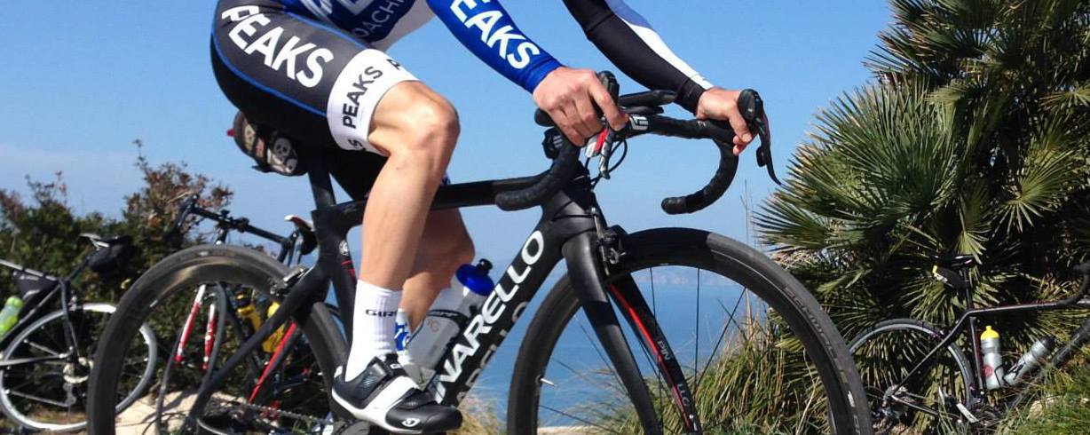 A man is riding a bike with the word peaks on his jersey