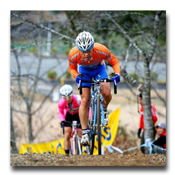 A man wearing a helmet is riding a bike on a dirt road