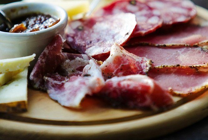 A close up of cured meats, cheese and dips