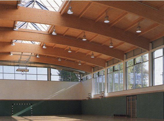 Eine große Turnhalle mit Holzdecke und vielen Fenstern