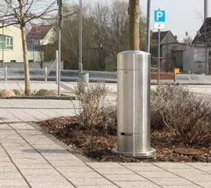 Auf dem Bürgersteig steht neben einem Baum eine Edelstahlstange.