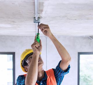 Electrician Wiring On Ceiling In Construction Site — North Alabama — Superior Electrical Service Inc. Electrician Wiring On Ceiling In Construction Site — North Alabama — Superior Electrical Service Inc.