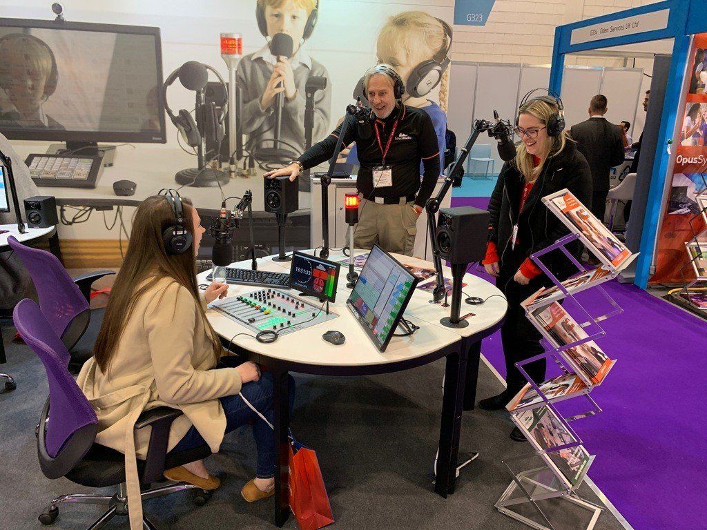 A group of people are sitting at a table in front of a microphone.