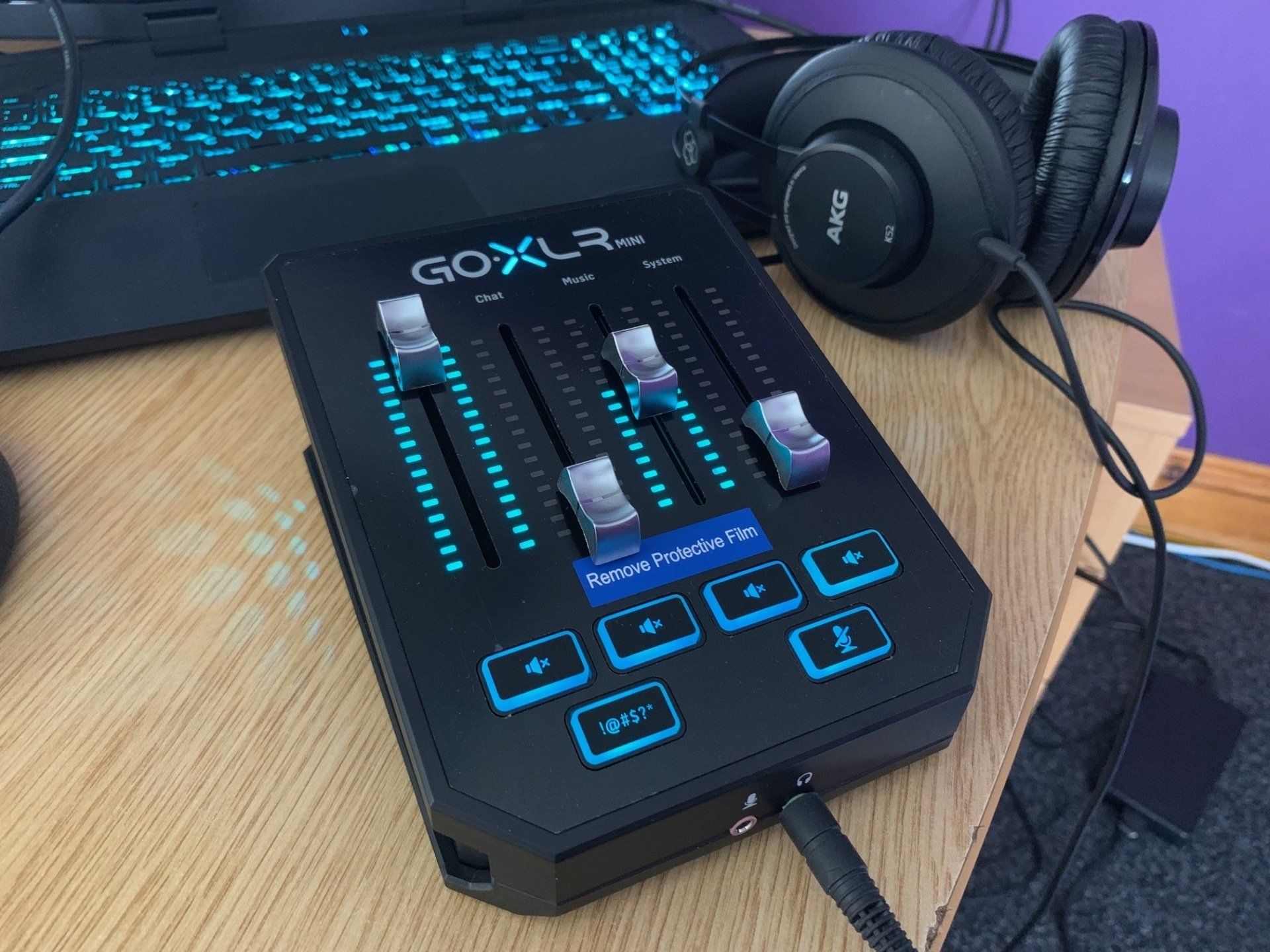 A pair of headphones are sitting next to a mixer on a desk.