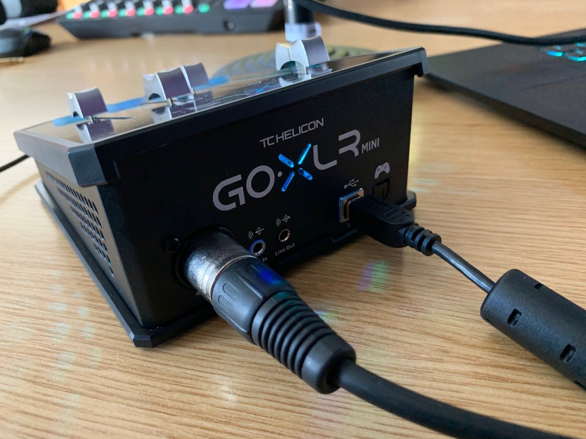 A go xlr is sitting on a wooden table next to a laptop.