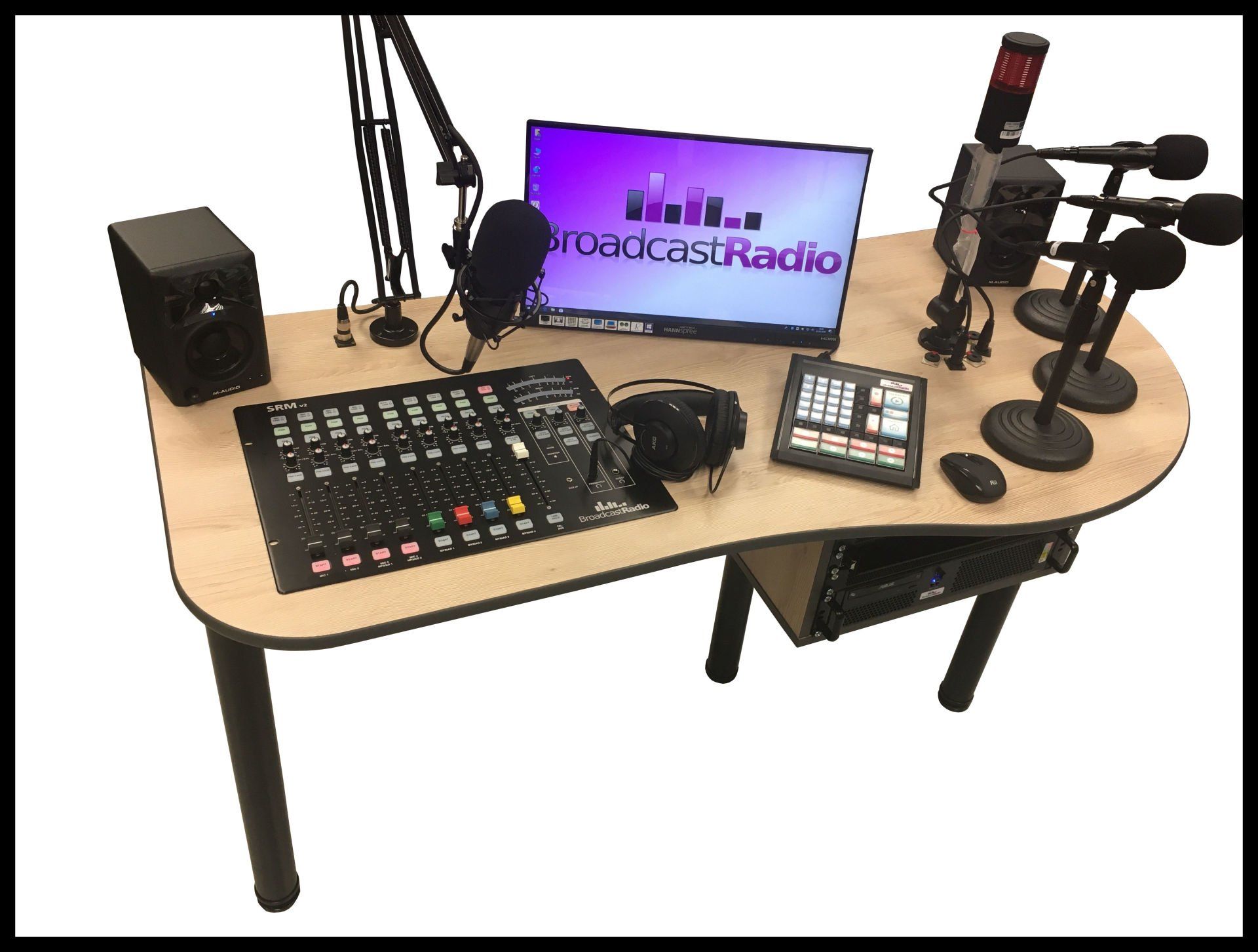 A desk with a monitor , mixer , and microphones on it.