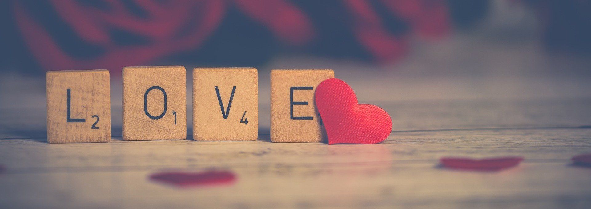 The word love is written on scrabble tiles next to a red heart.