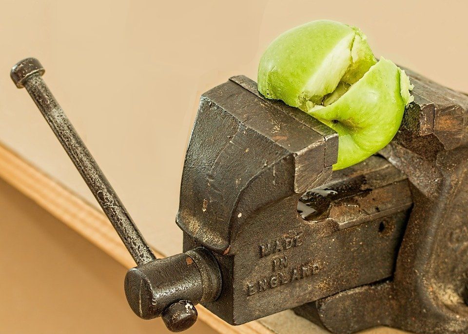 A green apple is sitting on top of a vise made in england