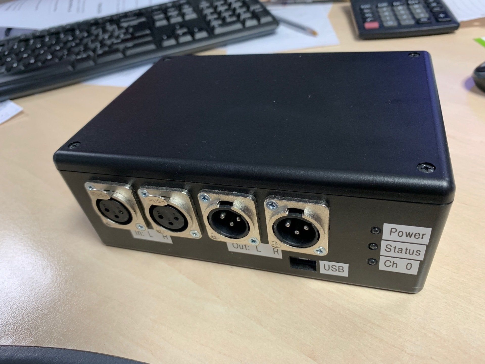 A black box with four holes in it is sitting on a wooden table.