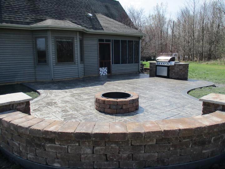 A fire pit in the middle of a patio in front of a house
