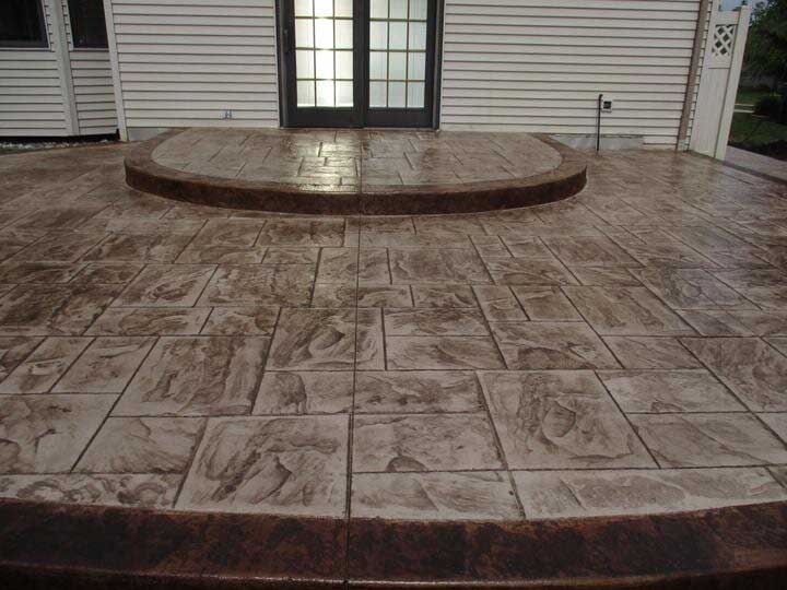 A concrete patio with a round step in the middle in front of a house