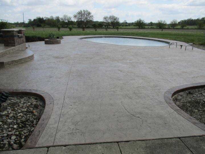 A concrete patio with a round swimming pool in the background