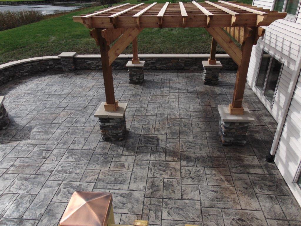 A wooden pergola is sitting on top of a stone patio