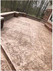 A concrete patio with a nice bench and steps in front of a house