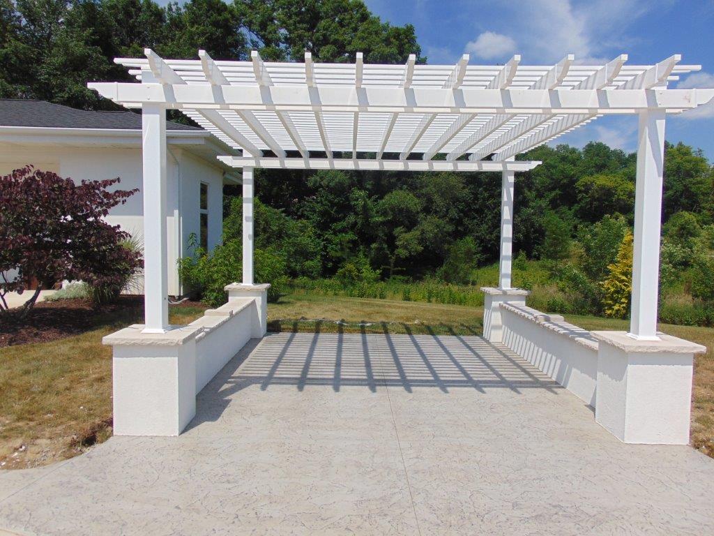 A white wooden pergola with a bench underneath it
