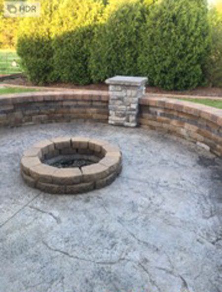 A patio with a brick fire pit in the middle