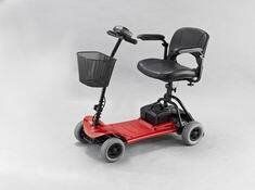 Red and black mobility scooter with a basket and seat on a white background.