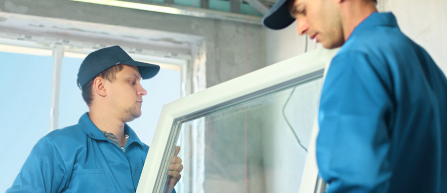 Two men are installing a window in a room.