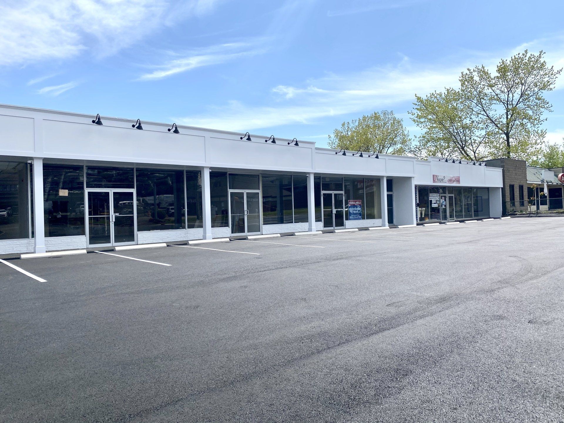 A strip mall with multiple storefronts under a blue sky.