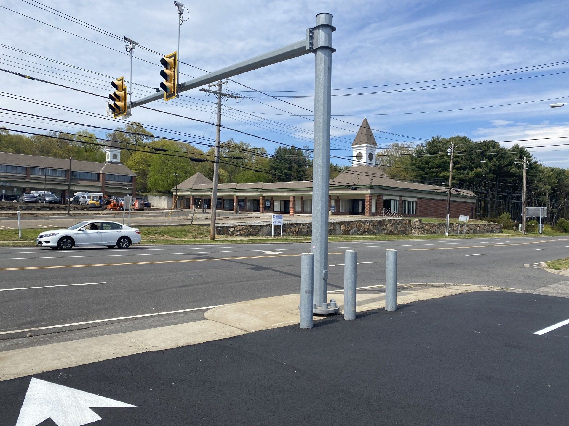 Intersection with traffic lights; a white car on the road; a building with a domed roof in the background.