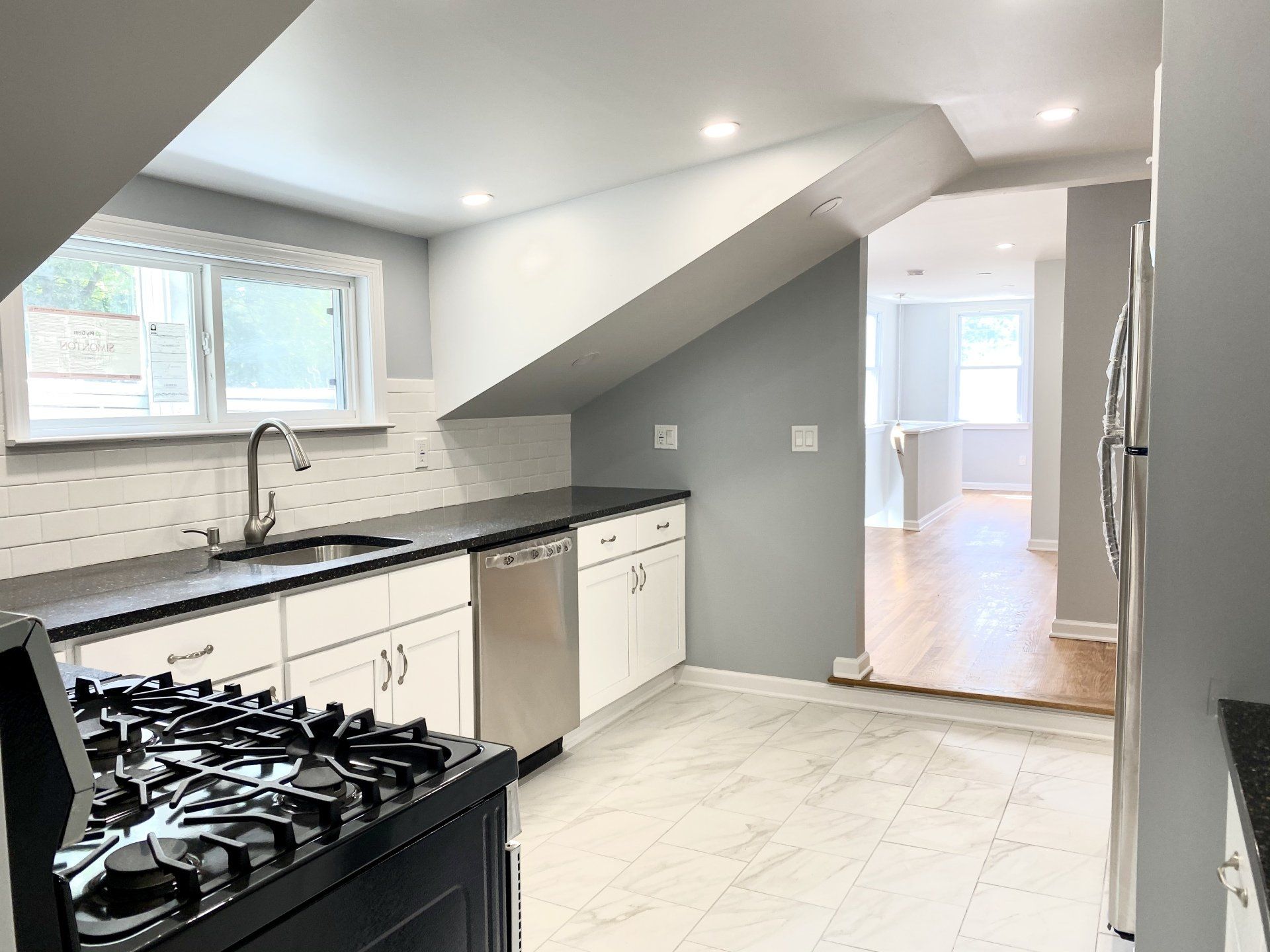 Newly renovated kitchen with white cabinets, stainless steel appliances, and dark countertops.