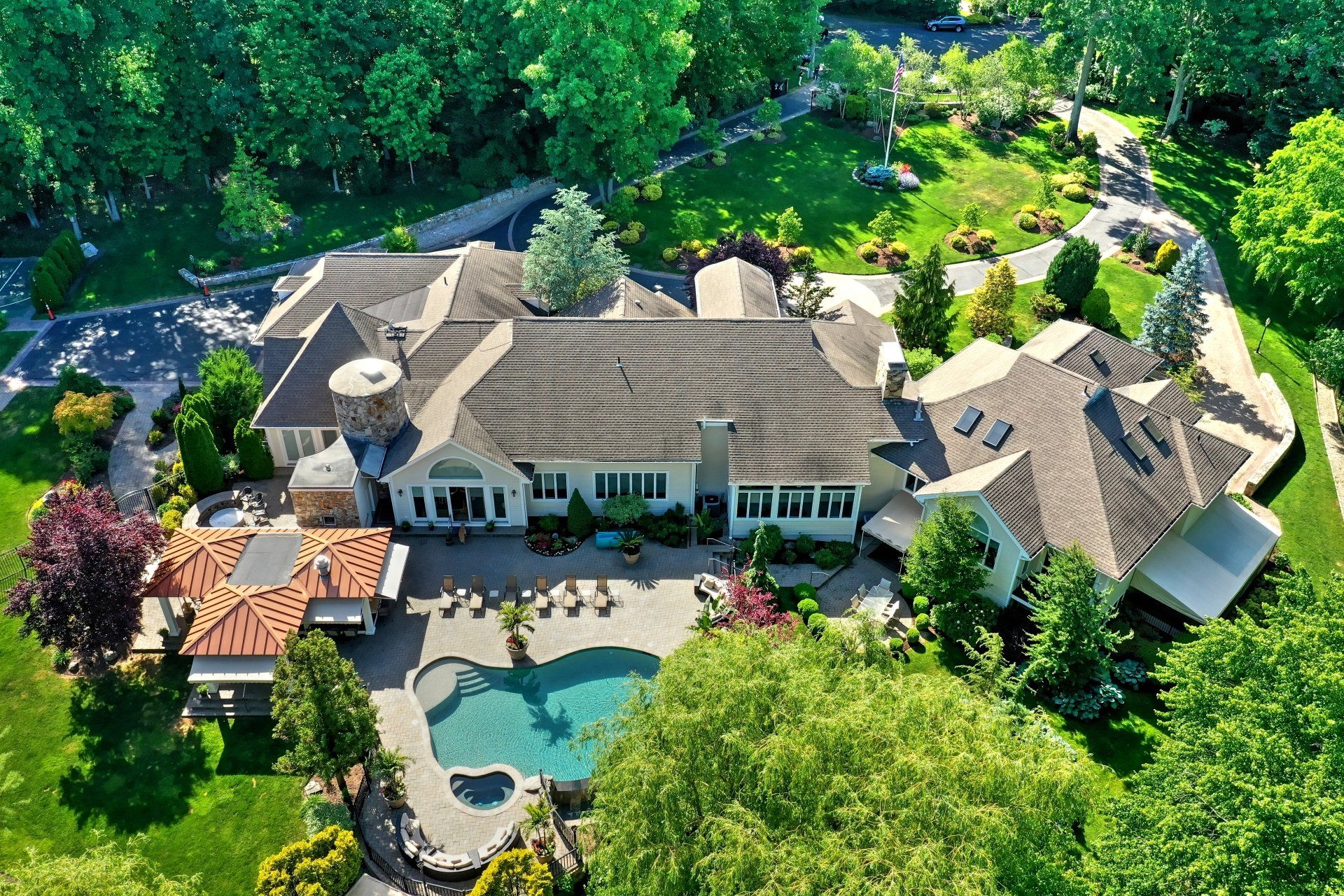 Aerial view of a large, luxurious house with a pool and lush landscaping.