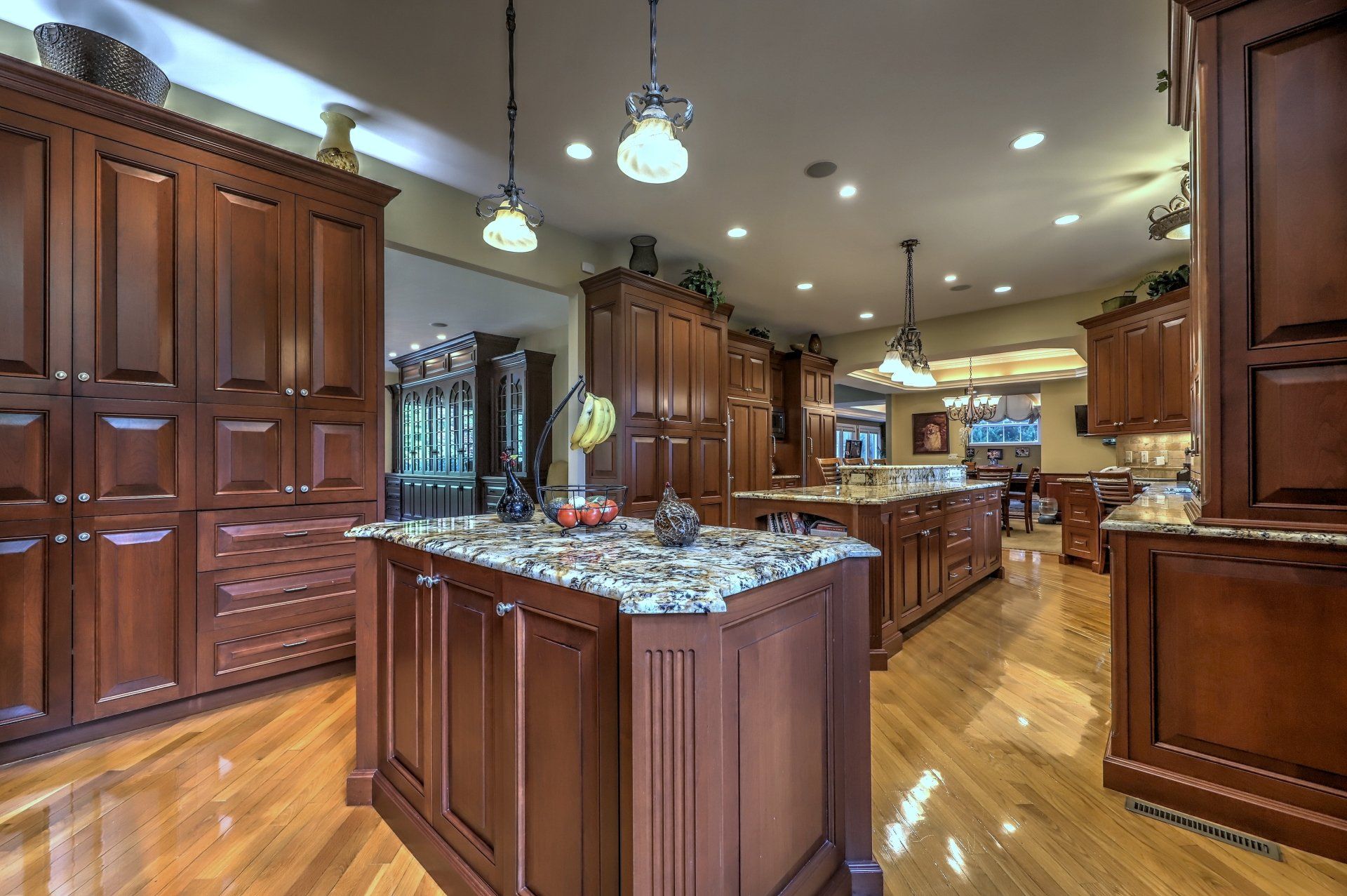 Spacious kitchen with wood cabinets and islands, granite countertops, and wood floors.