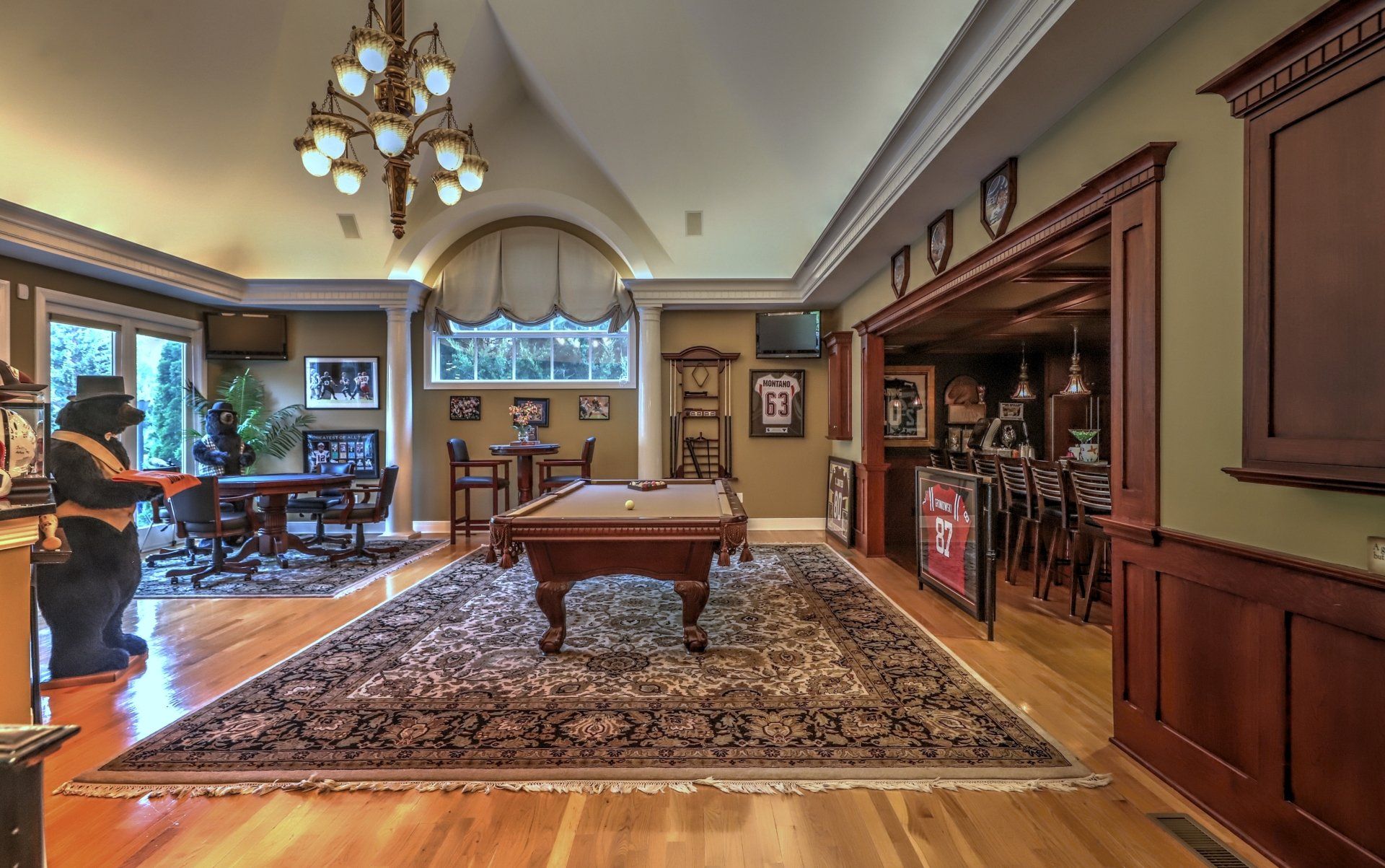 Upscale recreation room with a pool table, bar, seating, and decorative elements.