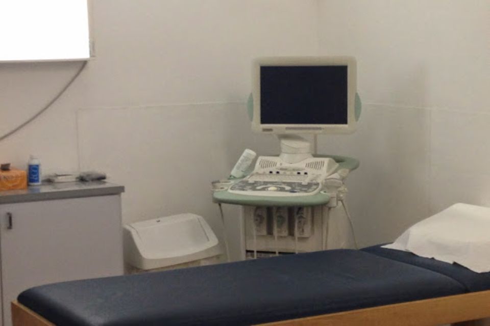 Ecografo e lettino per visite in una sala clinica.
