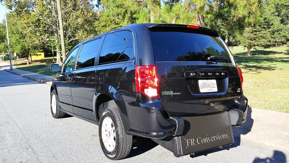 A black minivan is parked on the side of the road.
