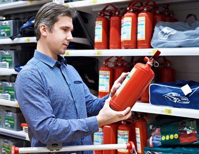 Kitchen Fire Extinguishers — Man Looking On A Fire Extinguisher In Keswick, VA Kitchen Fire Extinguishers — Man Looking On A Fire Extinguisher In Keswick, VA