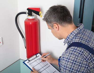 Garage Fire Extinguishers — Worker Checking On A List Of Fire Extinguisher In Keswick, VA Garage Fire Extinguishers — Worker Checking On A List Of Fire Extinguisher In Keswick, VA