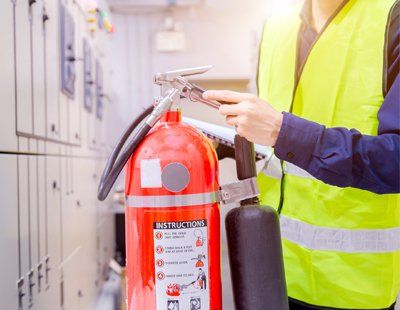 Oil File Extinguishers — Worker Checking On The Pin Of Fire Extinguisher In Keswick, VA Oil File Extinguishers — Worker Checking On The Pin Of Fire Extinguisher In Keswick, VA