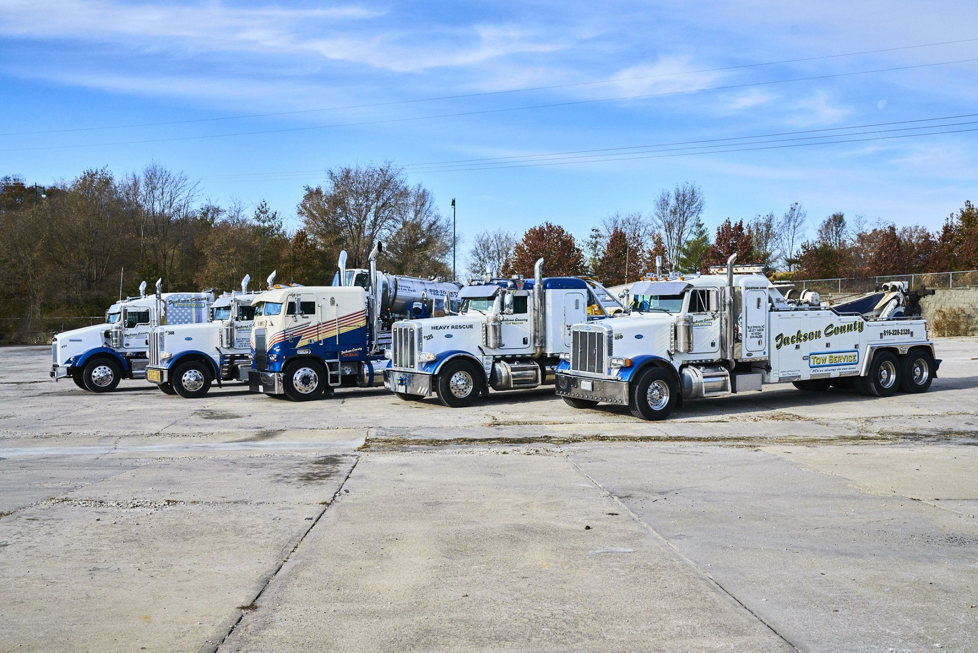 Two white tow trucks parked side by side on a snowy lot under a clear sky