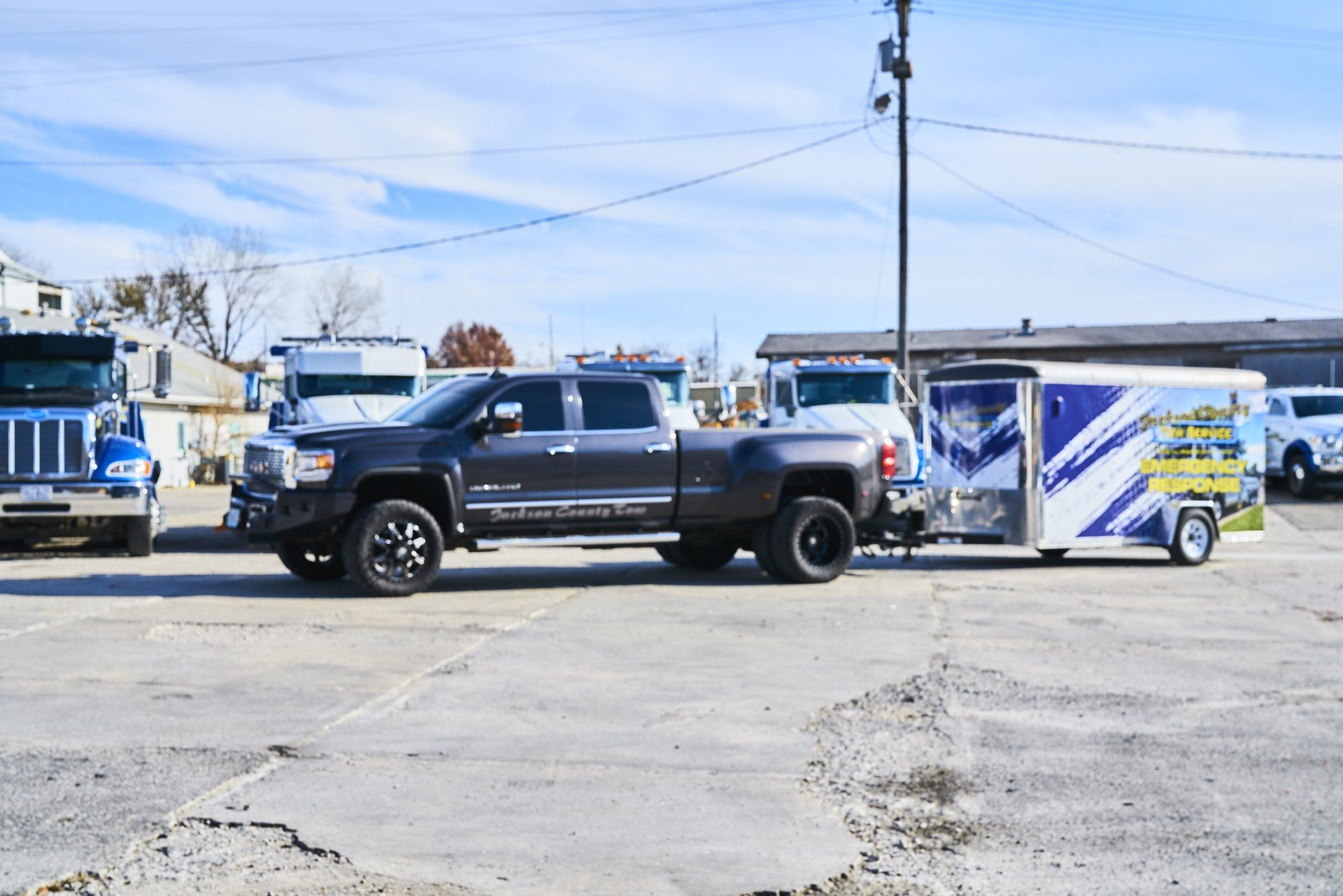 Black pickup truck towing a white and blue trailer on a sunny roadside.