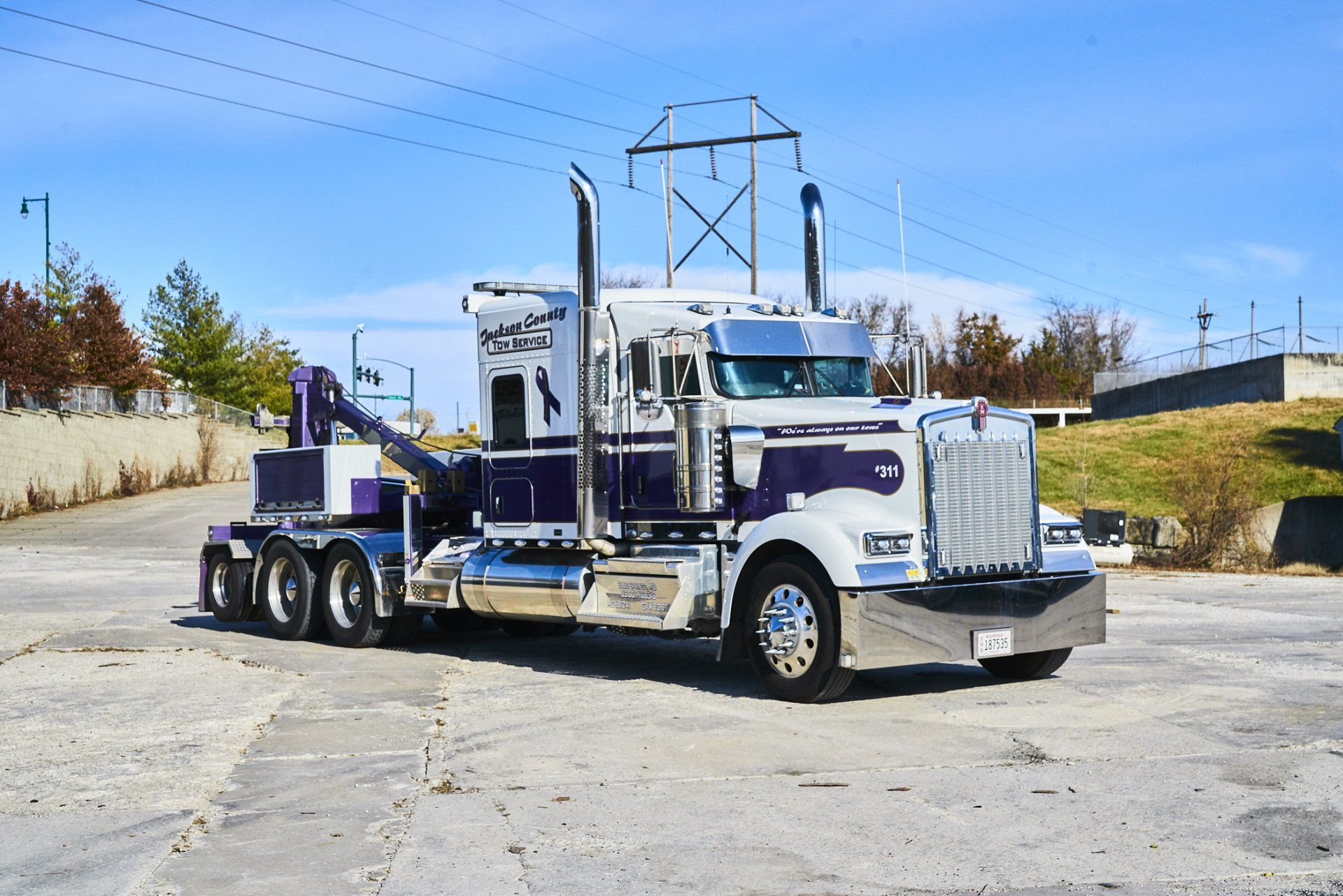 White semi-truck with purple accents parked on a sunlit lot under a blue sky