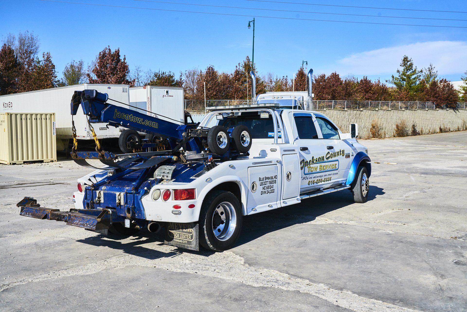 Tow truck with blue crane parked in a lot under a clear sky