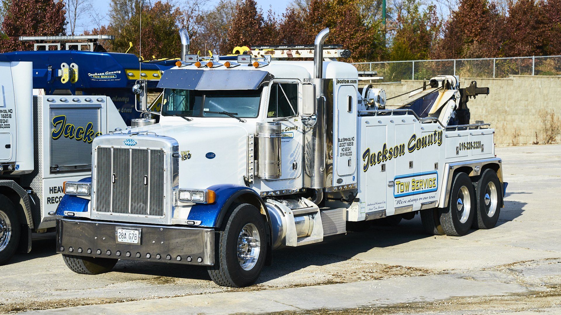 White tow truck with blue accents parked outdoors on a sunny lot