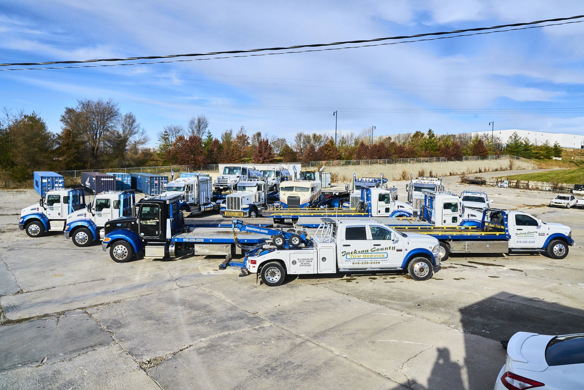 Tow trucks lined up in a parking lot under a clear blue sky