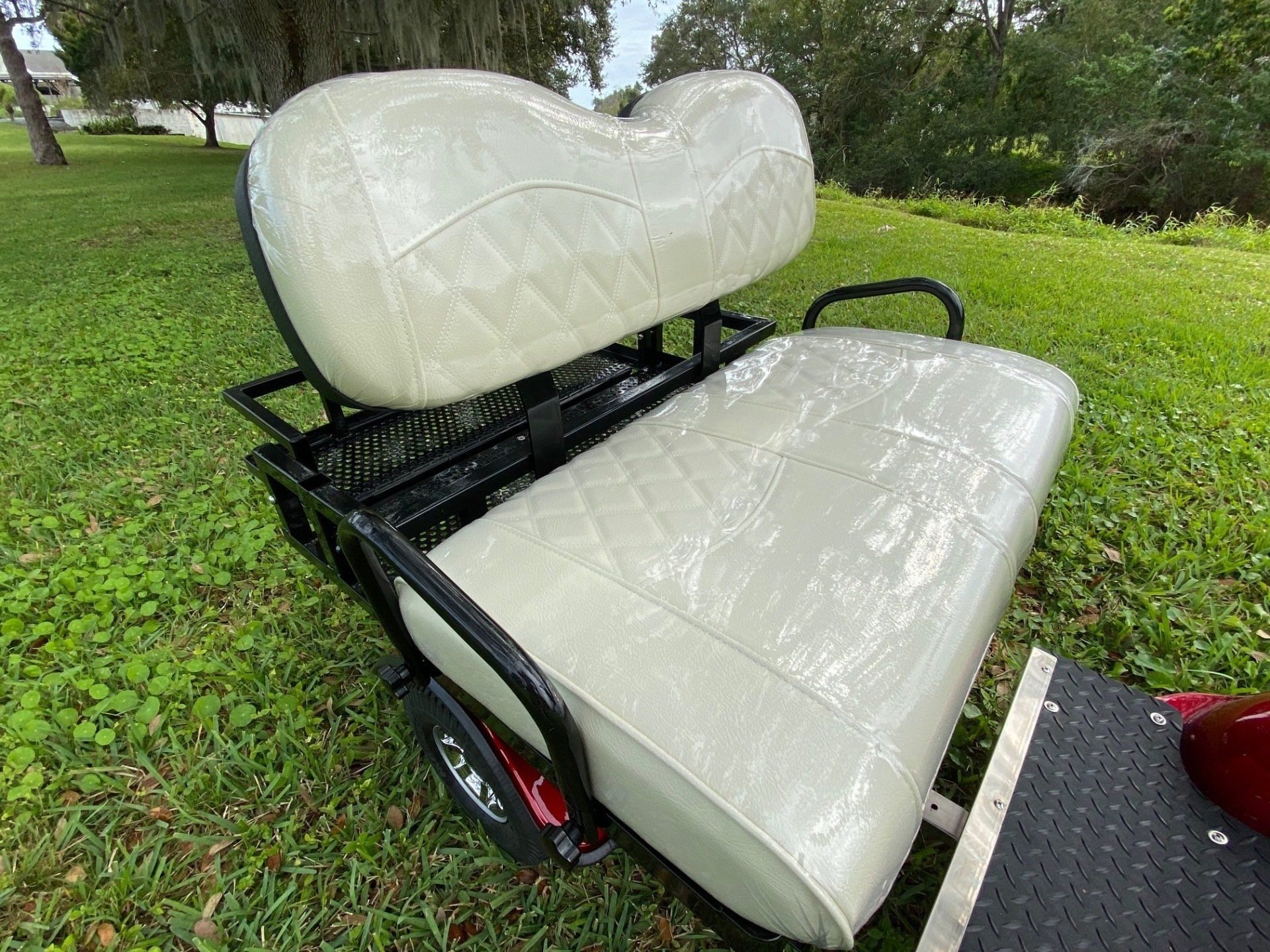 A white golf cart seat is sitting on top of a lush green field.