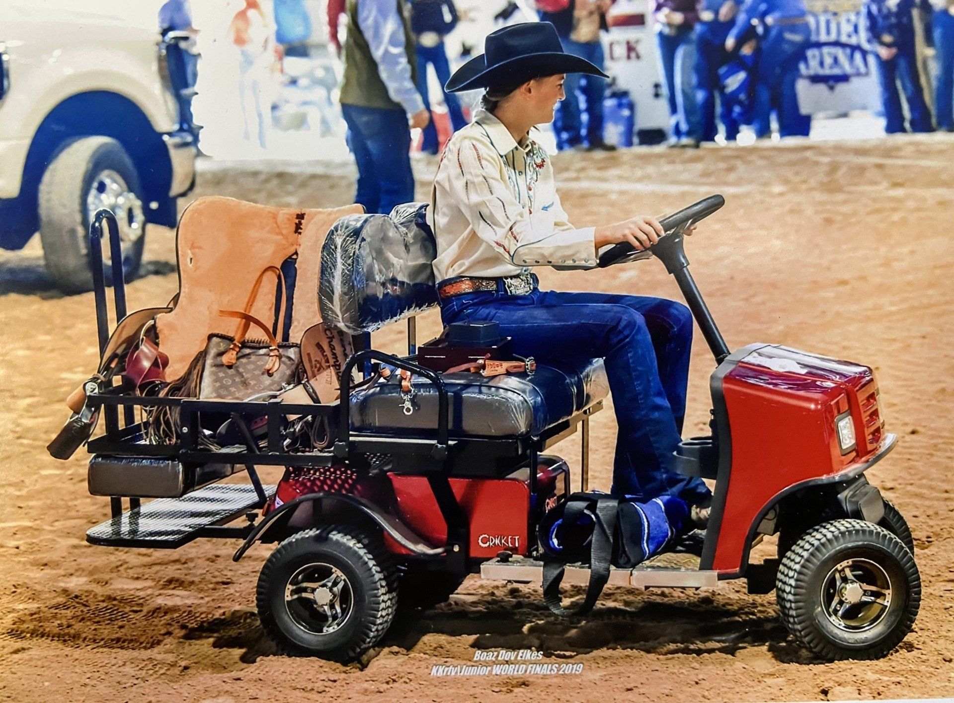 A man in a cowboy hat is riding a golf cart
