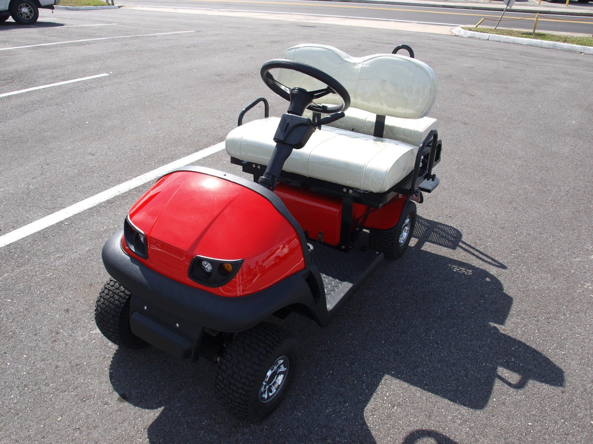 A red golf cart with white seats is parked in a parking lot