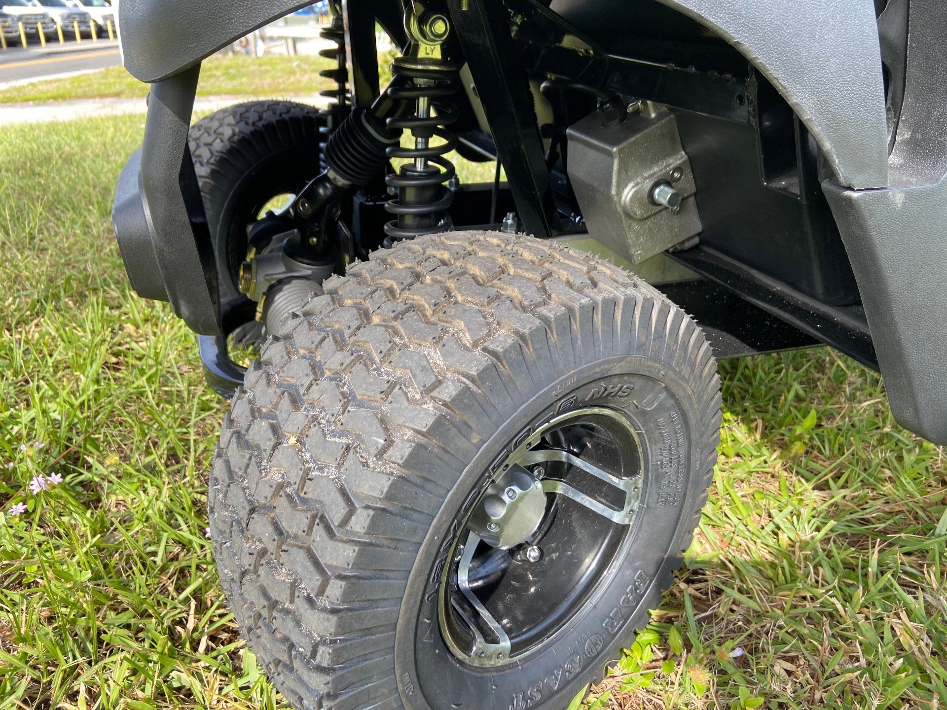 A close up of a golf cart wheel on a grassy field.