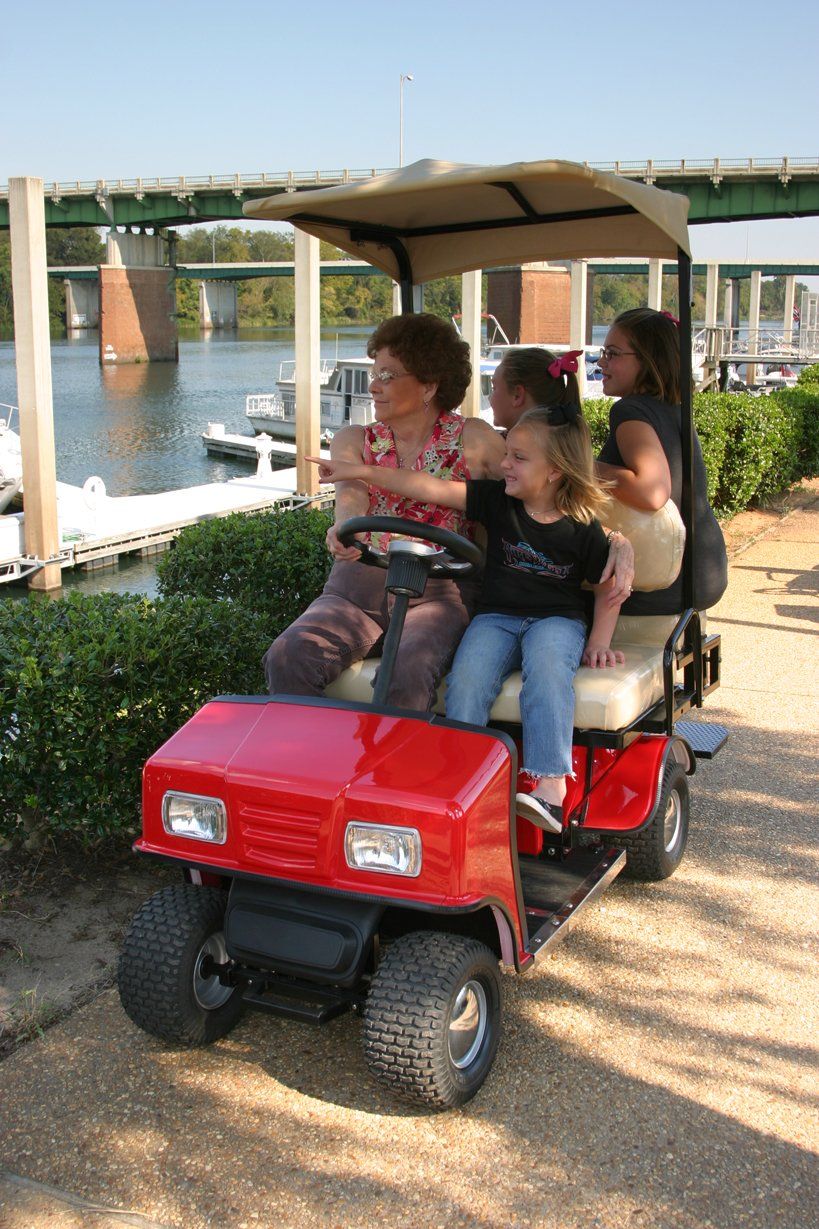 A group of people are riding in a red golf cart