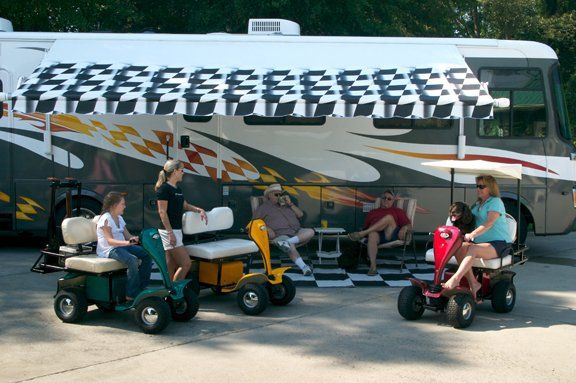 A group of people are sitting on golf carts in front of a rv