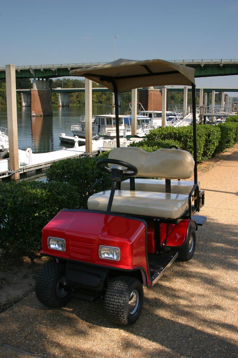 A red golf cart is parked next to a body of water.
