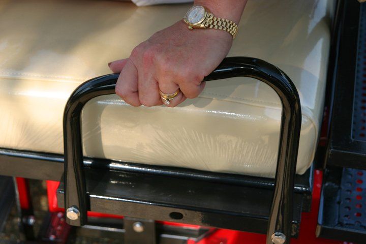A woman wearing a watch is holding the handle of a golf cart