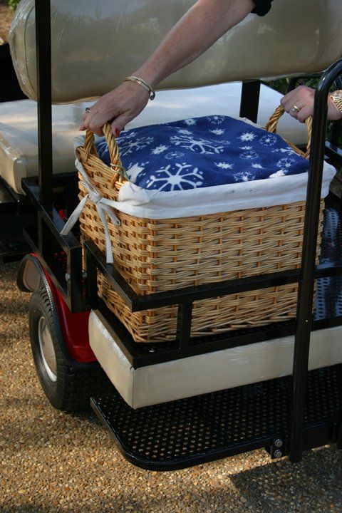 A person is putting a basket on the back of a golf cart