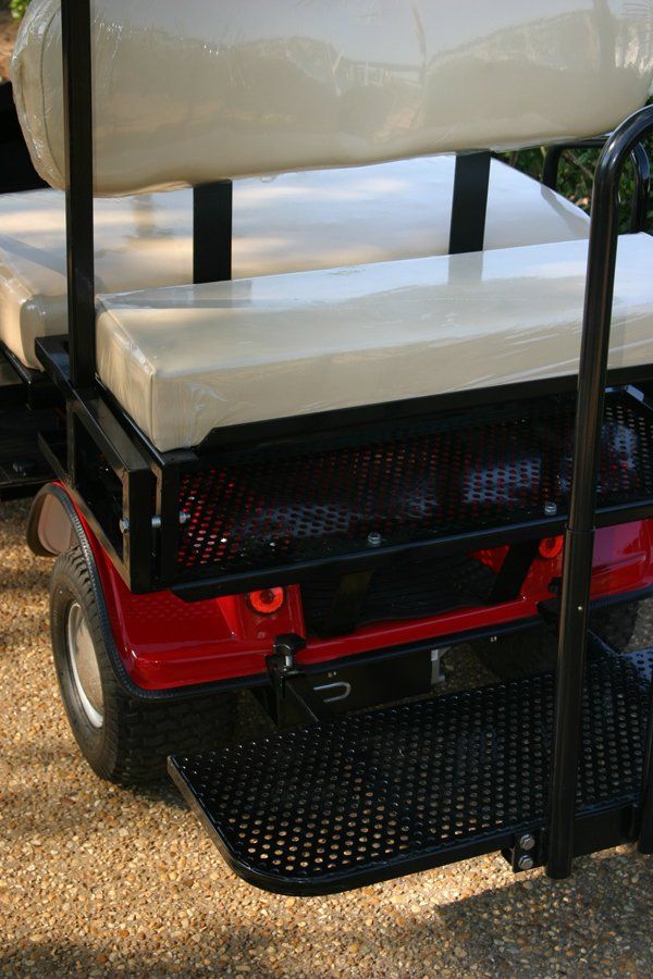 A red golf cart with white seats is parked on the side of the road.